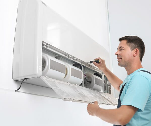 DunRite Heating & Air Inc. - technician fixing modern air conditioner