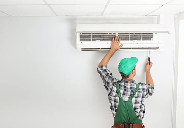DunRite Heating & Air Inc. - technician fixing modern air conditioner