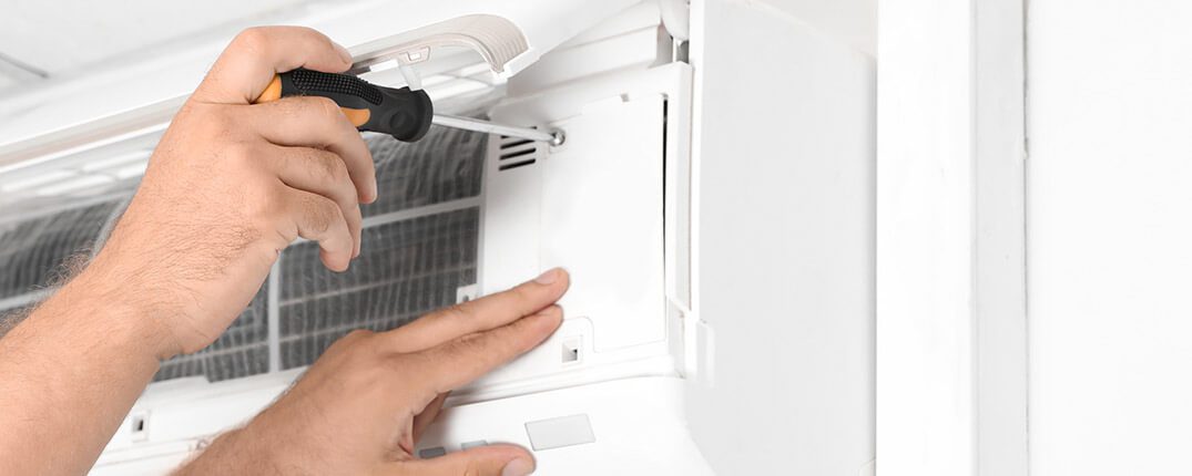 DunRite Heating & Air Inc. -technician fixing modern air conditioner