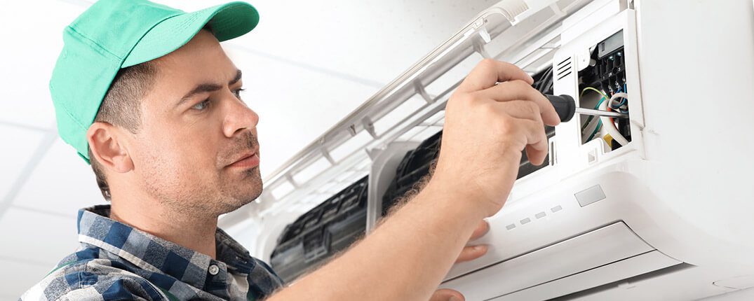 DunRite Heating & Air Inc. - Male technician repairing air conditioner
