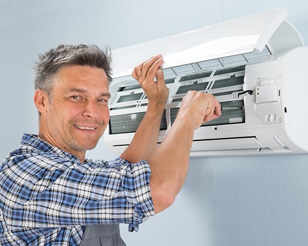 DunRite Heating & Air Inc. - Happy male technician repairing air conditioner